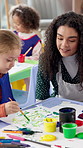 Education, painting or school with student and teacher in classroom for development, learning or study. Art, children and teaching with kid and woman at desk for creative course or lesson together