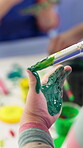 Student, child and painting on hand in classroom for creative project, art lesson and coordination skills. Kindergarten, closeup and paintbrush for messy color artwork, education or motor development