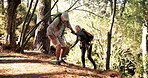 Senior couple, hiking or helping hand in forest for support, trip or outdoor journey together. Elderly, man or assisting woman with backpack, care or hill for difficult path, trekking trail or woods