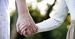 Closeup, holding hands and walking with parent for generation, bonding or journey together in nature. People, love and strolling with touch for forest adventure, youth or growth in outdoor woods