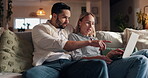 Laptop, pointing and relax with couple on sofa in living room of home together for evening bonding. App, computer or conversation with man and woman in apartment at night for internet browsing