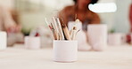 Pottery, art and mug with tools in workshop of artistic process, sculpture design and learning artwork. Closeup, people and equipment for craft production, handmade hobby and creative lesson in class