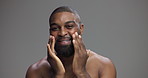 Face, skincare and black man with cream in studio for collagen treatment, shine or dermatology. Portrait, moisturizer and happy person apply cosmetics for hydration, glow or beauty on gray background