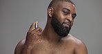 Smile, black man and face with perfume in studio, hygiene and body fresh scent with confidence. Space, male person and portrait with cologne for fragrance, cosmetics and self care by gray background