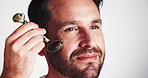 Man, skincare and jade roller in studio with cosmetics, routine and process for anti aging by white background. Mature person, model and tools with stone, circulation and happy for facial beauty