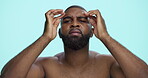 Skincare, black man and check face in studio for grooming routine, acne treatment results and forehead pores. Serious, person and skin inspection on blue background for blemish healing and anti aging
