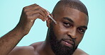 Serum, skincare and face with black man in studio for beauty cosmetics, dermatology and self care. Clean, glow and oil with person and dropper on blue background for hydration, vitamin c and shine