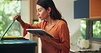 Tablet, recycling and woman in kitchen in home for sorting trash, cleaning or housekeeping. Bins, digital technology and female person organize dirt in containers for social responsibility or hygiene