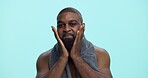 Moisturizing, oil and man with beard, face and grooming with cosmetics in morning, studio or space. Blue background, fresh shave and black person with routine for self care, happy or facial treatment