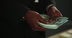 Hands, fraud and counting cash for money laundering, capital and investment scam in crime syndicate. Night, closeup and person with dollars from criminal activities, corruption or illegal business