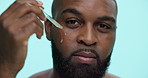 Black man, face and dropper with oil serum in studio for collagen or vitamin C on a blue background. Portrait, male person or happy model with smile or pipette for facial dermatology or anti aging