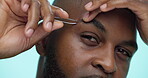 Eyebrows, grooming and tweezers with black man in studio for beauty or skincare routine. Aesthetic, face and hair removal with African person on blue background for cosmetics, cleaning or hygiene