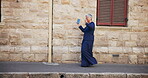 Happy, woman and dancing with earpods in city for listening to music, streaming audio and travel fun. Mature person, rhythm and moving with energy for playlist, morning commute and freedom of journey