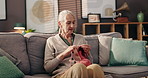 Hobby, calm and senior woman knitting in home for mental engagement, activity or creativity. Relax, retirement and elderly female person with needles and wool for handmade clothes in living room.