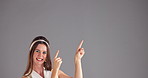 Face, pointing and woman in studio, smile and promotion with confidence on gray background. Portrait, happy person and model with hand gesture, mockup space and contact us with opportunity and sales
