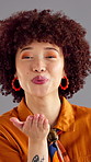 Happy woman, face or blowing kiss with afro for love, affection or distance on a gray studio background. Portrait, female person or model with smile or romantic gesture for flirt, fashion or beauty