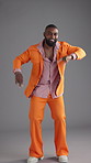 Face, dancing and black man with retro fashion, colourful and energy on gray background. African person, model and vintage outfit with movement, stylish wardrobe or smile with pride or trendy clothes