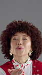Face, woman and air kiss for fashion, retro apparel with flirting and confident on gray background. Wink, portrait and African person with afro, vintage style or lips with blowing gesture in studio
