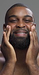 Moisturizing, skincare and man with cosmetics, studio and self care with facial treatment or smile. Gray background, healthy and black person with routine for glow, dermatology or grooming in morning