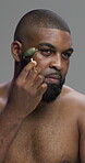Black man, jade roller and skincare for beauty in studio for lymphatic drainage, anti aging and self care. Male person, tools and facial massage of dermatology, treatment benefits and gray background