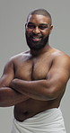 Face, happy man and confident for skincare, body care or arms crossed with towel. Portrait, shirtless or African male model with cosmetics for hygiene, beauty or dermatology on gray studio background