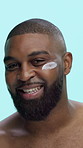 Black man, smile and lotion on face in studio for skincare, cosmetics or moisturizer on blue background. Happy, portrait and male person with cream, sunscreen or facial treatment for dermatology
