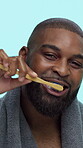 Black man, face and toothbrush for brushing teeth in studio, smile and bamboo on blue background. Dental health, oral care and fresh breath with male person, towel and routine with toothpaste