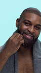 Face, smile and black man with comb for beard, grooming and wellness with healthy growth or texture in studio. Happy, portrait and male person with brushing facial hair and pride on blue background