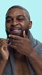 Face, smile and black man with oil for beard care, grooming and wellness with healthy growth or texture in studio. Towel, portrait and person with essence, facial hair and health on blue background