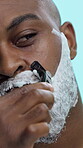 Face, closeup and black man with foam for shaving, skincare or morning routine for grooming in studio. Hygiene, cosmetics and razor for hair removal, cream or soap for epilation on blue background