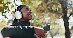 Headphones, thinking and black woman in park for fitness, exercise and training outdoor. Happy, thoughtful and person resting and listening to audio, music and podcast for wellness, health and break