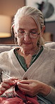 Senior woman, relax and knitting in home for hobby, creativity and recreation in retirement. Elderly person, needles and wool on sofa for homemade clothing, mental stimulation and crafting skills