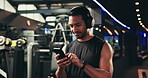 Gym, fitness and man with smartphone for music, podcast and streaming online for workout motivation. Exercise, male person and smile with cellphone for application, audio track or headphones at night