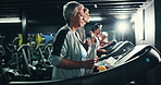 Mature, woman and treadmill in gym with smart watch, water bottle and towel for sweating with intense workout. Hydration, check progress time and fitness with machine, walking or steps for cardio