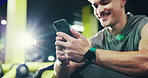 Fitness, gym and man relax with phone for exercise schedule, track health and reading online. Mobile, break and happy bodybuilder in club for wellness app, training progress and typing text message
