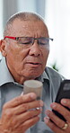 Hands, phone and pills with elderly man for healthcare, check online for dosage, prescription and reading medical label. Home, telehealth instruction or pharmaceutical details for tablets on web