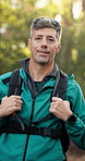 Face, happy and man with hiking in forest for travel adventure, sightseeing nature or hobby. Trekking, mature person and backpack in woods with laughing, holiday journey and exploring outdoor scenery