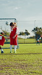 Free kick, children or football player with goal for winning at game and match in kids tournament. Sports, exercise and back of soccer athlete shooting ball in net at practice on field at stadium