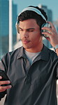 Phone, fitness and man with headphones in city for music, streaming podcast or motivation playlist. Happy athlete, mobile and outdoor for sound, song and runner listening to audio on exercise break