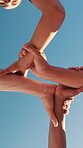 Hands, unity and below people by blue sky for cooperation, solidarity with community and team building. Huddle, link or support with partnership, synergy and group joining in circle for trust outdoor