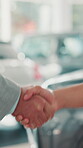 Deal, car and purchase with handshake of people at dealership for test drive, auto showroom and vehicle decision. Salesman, keys and shaking hands with closeup of customer for rental agreement