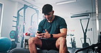 Break, fitness and man with phone in gym rest after exercise, training and workout routine. Sports health club and happy person relax on smartphone for typing message, social media and connection