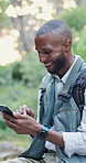 Phone, nature and black man hiking in forest with laugh, social media and mobile app meme. Smile, technology and male person typing on cellphone trekking in outdoor woods for exploring or adventure