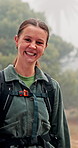 Happy woman, face and hiking with backpack in forest, fog or mist for winter adventure or journey. Portrait, female person or hiker with smile in nature for trekking, walk or outdoor trip in woods