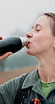 Woman, hiker and drinking with water bottle in nature for hydration or natural sustainability. Active, female person or hiking with mineral liquid, aqua or beverage for thirst, rest or break in woods