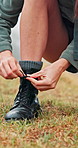 Woman, hands and tying boots for hiking preparation, safety or trekking adventure on grass field. Closeup, female person or hiker getting ready with shoes, tie or laces for journey or walk in nature