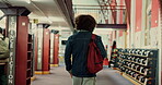 Man, education and student walking in library for study material, textbook search and knowledge. Back, person and backpack on college campus for assignment information, thesis citation or scholarship