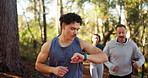 Man, smart watch and trail running in forest with group, challenge and stats for training in summer. Person, stopwatch and friends with timer, workout and exercise on path in woods for wellness