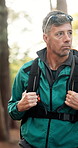 Hiking, man and walking in forest with backpack for travel adventure, explore nature and fresh air. Trekking journey, mature person and sightseeing woods for environment scenery and wellness hobby