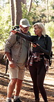 Senior couple, hiking and phone in woods with search for direction, point or landmark on adventure. People, smartphone and mobile app in forest for map, location or lost with conversation in Portugal